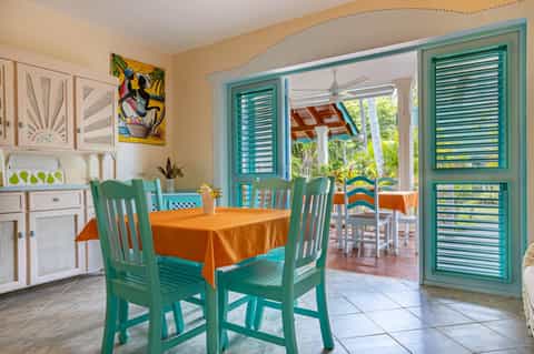 Colorful kitchen and dining area with turquoise doors, green chairs, and tropical patio views