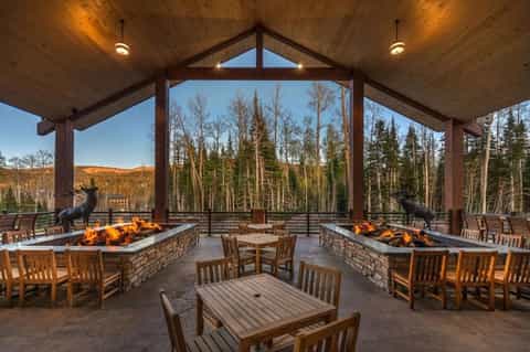 Covered outdoor pavilion with fire pits, wooden seating, and panoramic forest and mountain views