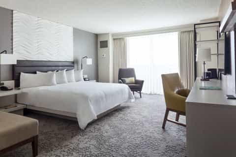 Modern hotel bedroom with king bed, contemporary furnishings, and balcony view