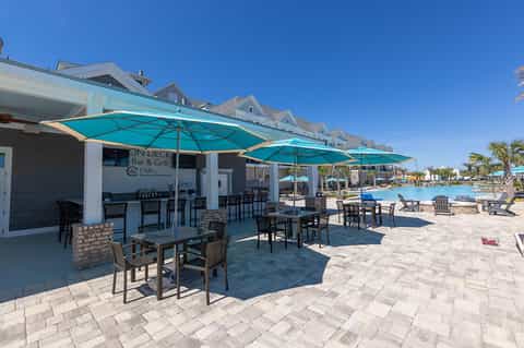 Beachfront bar and grill with turquoise umbrellas, patio seating, and ocean view