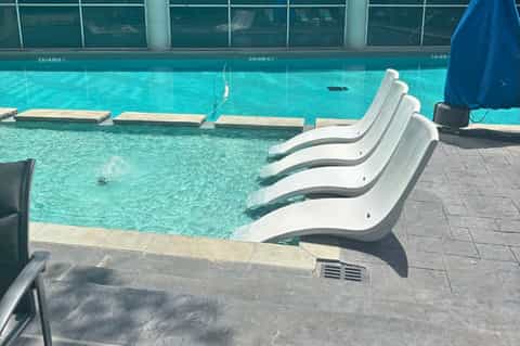 Indoor swimming pool with turquoise water and white curved lounge chairs along the edge