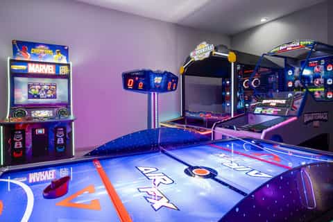 Game room with arcade machines, air hockey table, and neon lighting