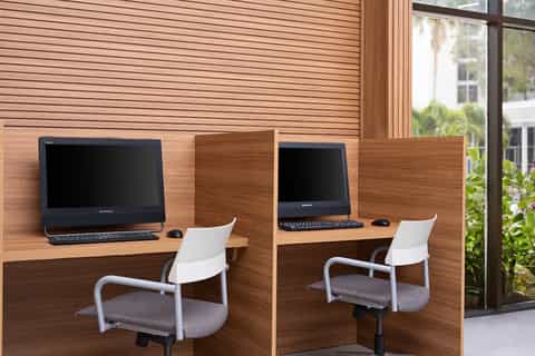 Modern business center with two computers, white chairs, and wood panel interior design