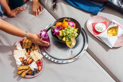 Overhead view of gourmet fruit platter and cocktail at upscale poolside dining table