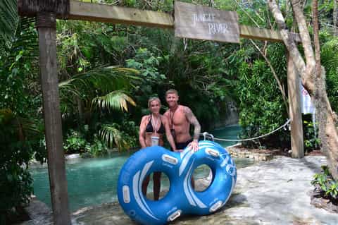 Couple at tropical jungle river attraction with blue floats and lush vegetation surrounding water