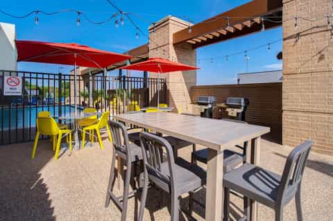 Rooftop terrace with red umbrellas, dining tables, and pool access
