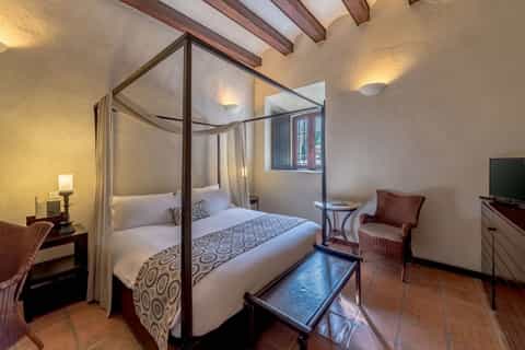 Elegant bedroom with four-poster canopy bed, exposed beams, and traditional decor