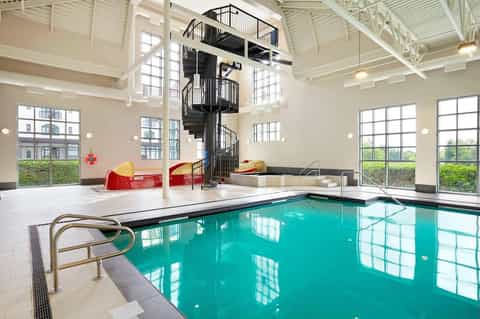 Indoor aquatic center with indoor pool, spiral staircase, and high ceiling windows