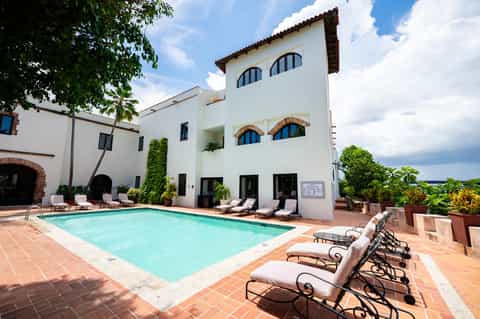 Spanish colonial-style hotel courtyard with turquoise pool and lounge seating