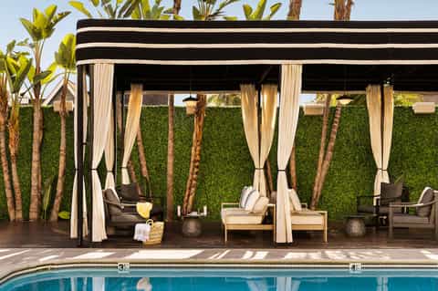 Modern poolside cabanas with black and white striped awnings and flowing white curtains