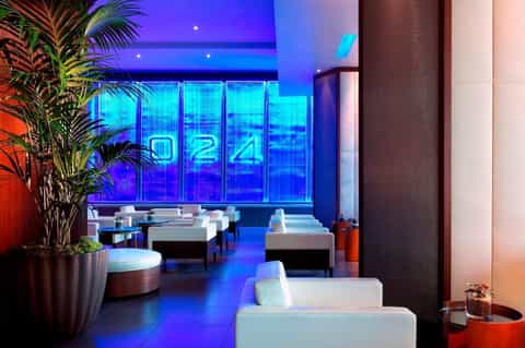 Modern spa lounge with blue neon lighting, white seating, and tropical plants