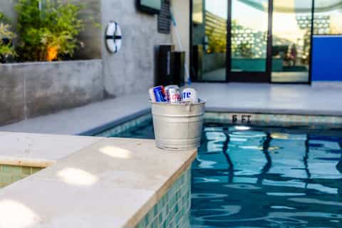 Metal bucket with beverages poolside overlooking outdoor swimming pool and courtyard