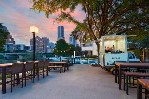Urban rooftop bar at sunset with cityscape, BAT BAR food truck, and river view
