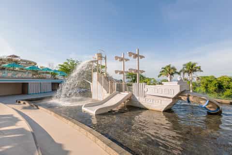 Playful water park area with white boat-themed playground structure and waterslide feature