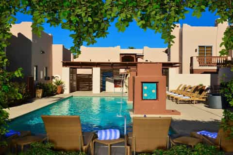 Courtyard pool surrounded by terracotta and cream buildings with lounge chairs and greenery