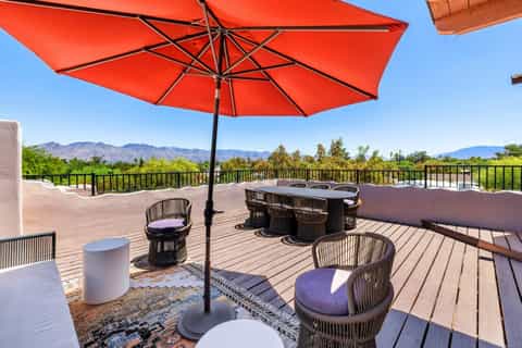 Rooftop terrace with red umbrella, lounge seating, and mountain valley views