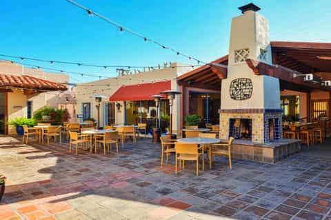 Spanish-style courtyard with terracotta tile flooring, fireplace, string lights, and wooden furniture