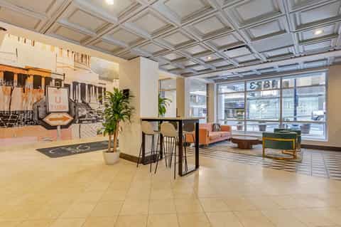 Contemporary hotel lobby with coffered ceiling, bar area, and street-facing windows