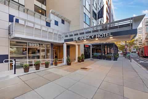 The Quincy Hotel storefront on urban street with modern glass and metal facade