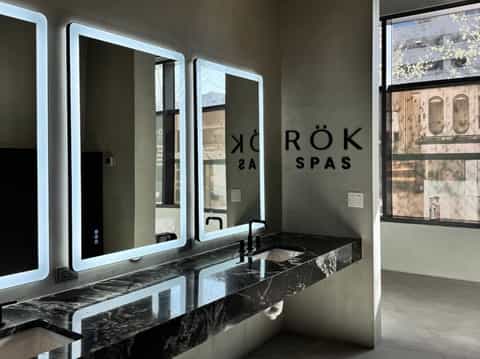 Modern spa bathroom with illuminated mirrors, black marble countertop, and contemporary design elements
