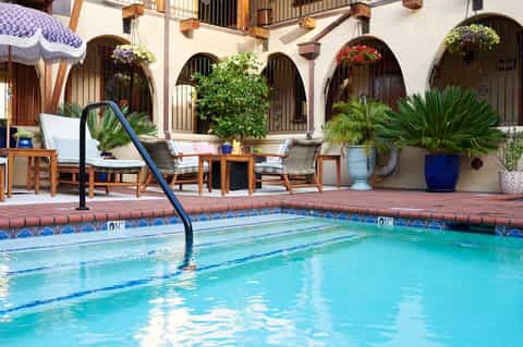 Resort courtyard pool with Spanish colonial arches, flowering plants, and lounge seating