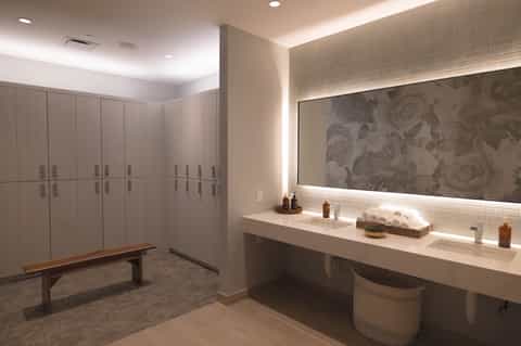 Spa locker room with white storage cabinets and illuminated vanity