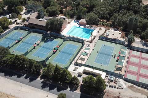 Aerial view of resort with Olympic swimming pool, tennis courts, and surrounding forested landscape