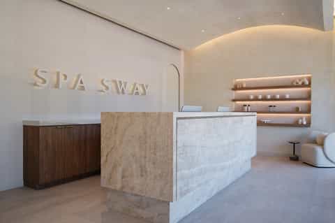 Modern spa reception desk with marble counter, wooden cabinetry, and ambient lighting