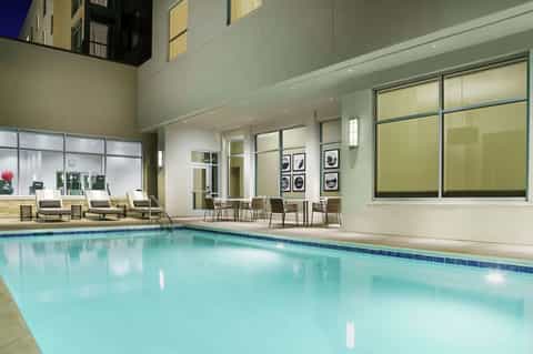Indoor heated pool with large windows, lounge chairs, and modern contemporary design