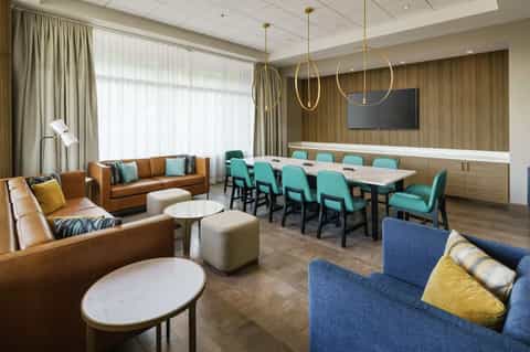 Modern hotel lounge with leather sofas, turquoise chairs, and conference table