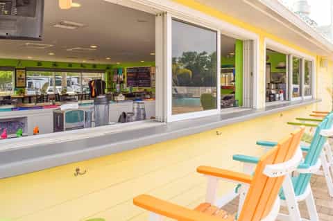 Colorful beach bar with yellow exterior, orange and turquoise chairs, and green interior