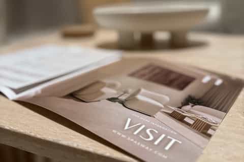 Close-up of spa brochure on marble surface with blurred spa imagery in background