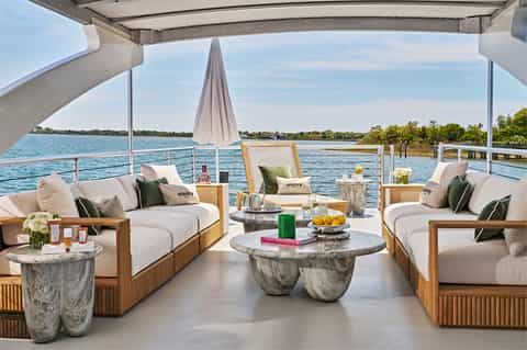 Luxury yacht interior lounge with cream seating, marble tables, and waterfront views