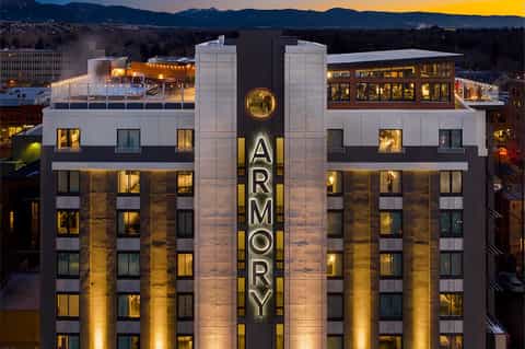 The Armory hotel building at night with historic facade, lit windows, and mountain backdrop