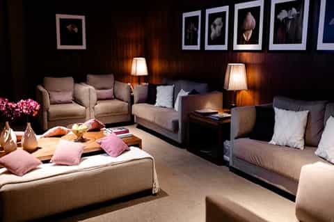 Luxury lounge with dark wood walls, comfortable seating, warm lighting, and floral artwork