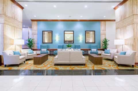 Modern hotel lobby with turquoise accent wall, cream furnishings, and decorative mirrors