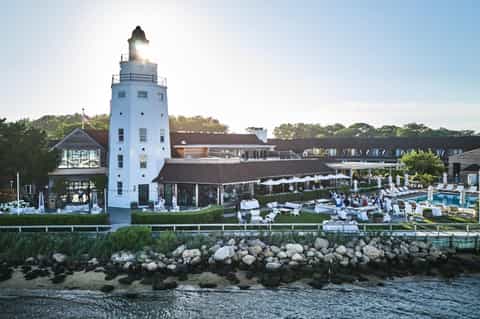 Coastal resort featuring white lighthouse tower, waterfront pools, and stone breakwater