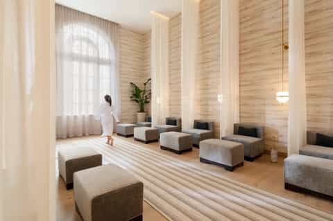 Serene spa relaxation room with natural wood walls, tall columns, neutral seating cubes, and large window