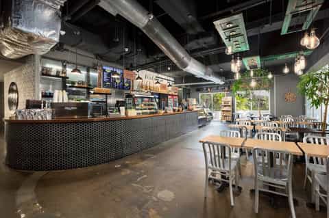 Modern cafe counter with hexagonal tile backdrop, pendant lighting, and dining area