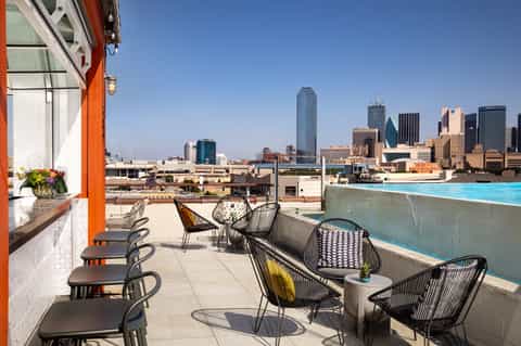 Rooftop bar and pool deck with city skyline views, modern seating, and blue pool