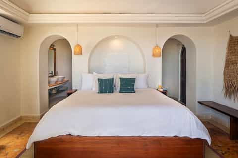Mediterranean-style bedroom with arched alcove headboard and pendant lighting