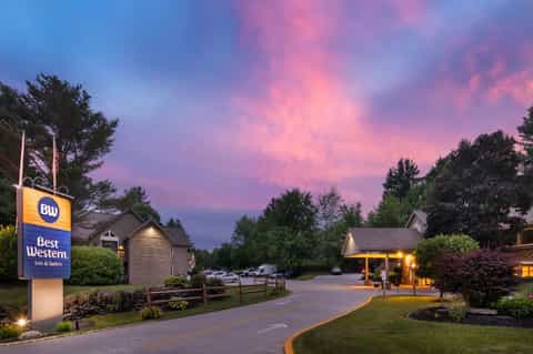 Best Western Inn & Suites entrance during purple sunset with landscaped grounds and trees