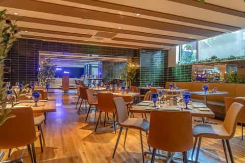 Modern hotel restaurant with warm lighting, copper chairs, tiled walls, and contemporary design