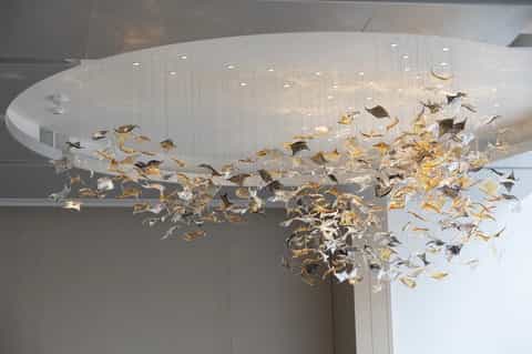 Dramatic chandelier with hundreds of gold and silver sculptural leaves in hotel lobby