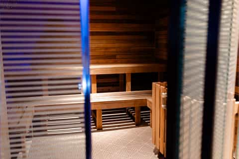 Modern sauna interior with wooden benches, blue accent lighting, and slatted wood details