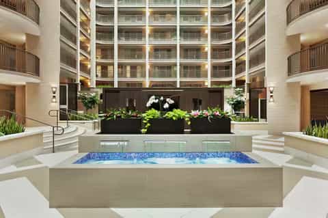 Multi-story hotel atrium with circular courtyard, indoor hot tub, planted flower beds, and surrounding balconies
