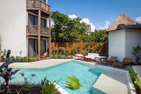 Private resort villa with turquoise pool, wooden deck, and thatched-roof structures