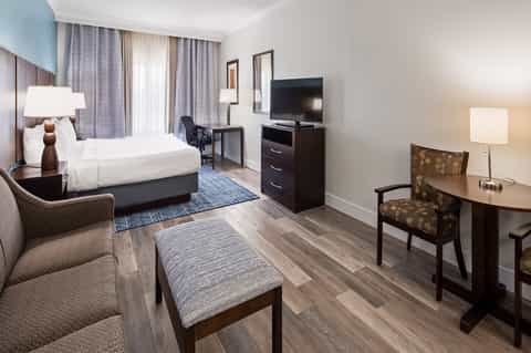 Contemporary hotel bedroom with bed, desk, TV, and seating area