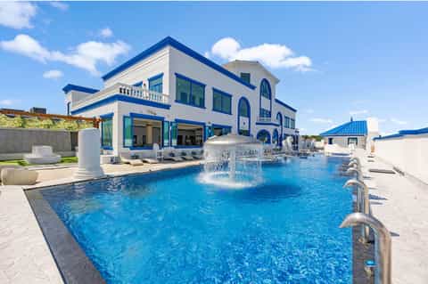 Modern blue and white resort building with fountain pool and sunbeds on expansive deck