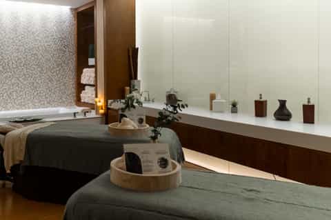 Spa treatment room with massage table, white vanity counter, and soaking tub